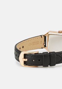 Schwarzes Lederarmband mit strukturierter Oberfläche, ausgestattet mit einer roségoldenen Metallschnalle und Gehäuse. Echtes Lederdetail ist innen sichtbar.