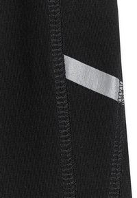 Gros plan sur un tissu noir avec une couture verticale et une bande diagonale argentée réfléchissante sur le côté droit.