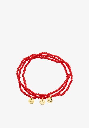 Rødt perlearmbånd med tre små runde guldsmykker jævnt fordelt, vist rullet sammen på hvid baggrund.