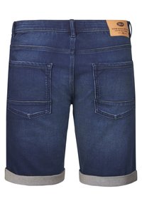 Tummansiniset farkkuhousut, joissa on käännetyt lahkeet, kaksinkertaiset takataskut ja nahkaleima vyötäröllä. Struktuuripintainen kangas.