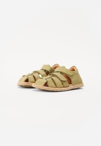 Rohelised nahast sandaalid on avatud disainiga, risti rihmadega, Velcro kinnitustega ja kummist tallaga, näidates mati tekstuuri ilma mustriteta.