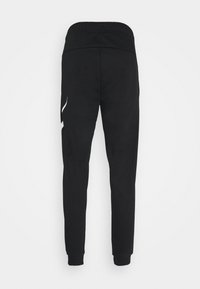 Joggings noirs de sport avec une texture douce, une taille élastique et des jambes fuselées. Présente un accent blanc sur le côté gauche.