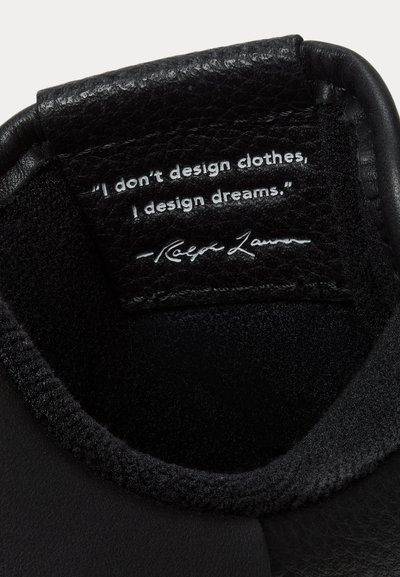 Citata ant juodos odos, esančios juodo batų apykaklėje: „Aš nesudarinėju drabužių, aš sudarinėju svajones.“ – Ralph Lauren.