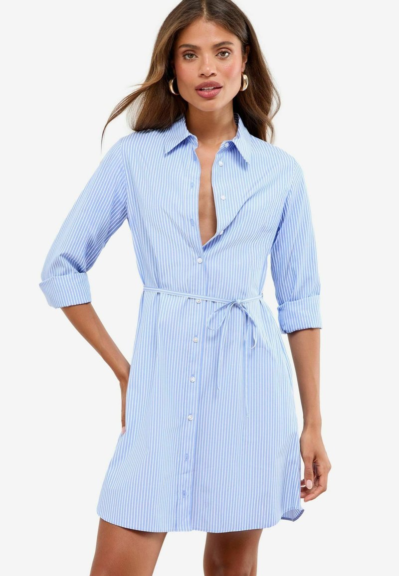 Abito a righe light blue e bianche con chiusura a bottoni frontale, colletto aperto, maniche arrotolate e vita legata per una silhouette aderente.
