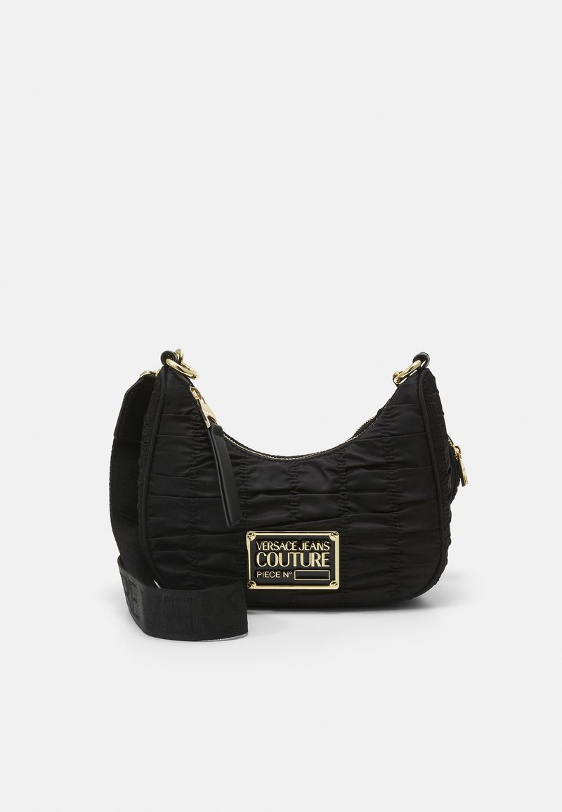 Sac d\'épaule noir en tissu matelassé avec des garnitures dorées. Il comporte une plaque logo et une large bandoulière avec des détails embossés.