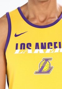 Débardeur Lakers en tissu jaune avec bordure violette, arborant les inscriptions "LOS ANGELES" et "LAKERS" imprimées en blanc et violet, avec un logo de ballon de basket.
