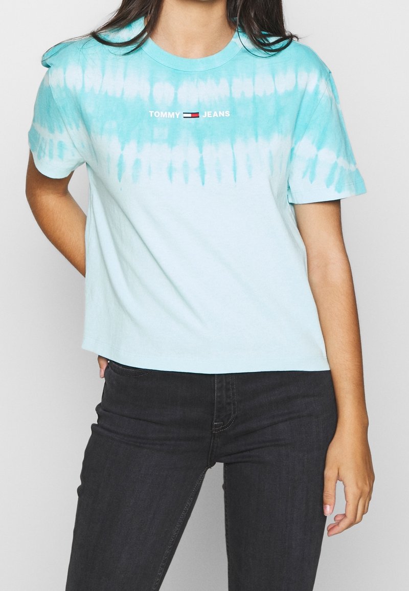 Světle modré tričko s efektom tie-dye, krátké rukávy, zkrácený střih, se znakem "TOMMY JEANS" v červené a černé barvě na hrudi.