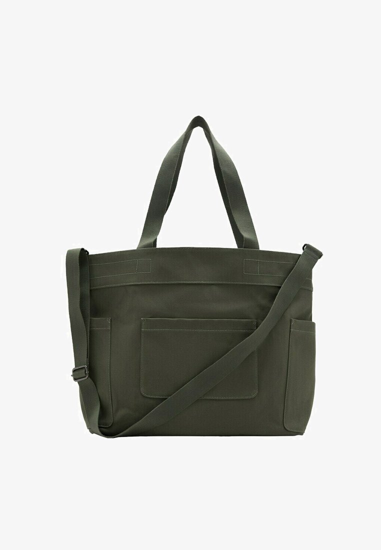 Donkergroene canvas tas met dubbele schouderbanden, voorvak en zijvakken, voorzien van verstelbare lange crossbodyriem.