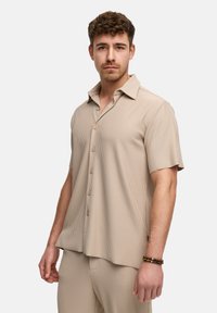 Korte mouwen, beige geribbelde shirt met een spread collar en knoopsluiting. Beschikt over subtiele verticale strepen en een losse pasvorm.