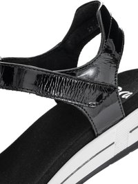 Black patent leather sandal strap with Velcro closure over a black cushioned footbed and white sole with textured grip.