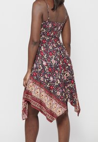 Robe à motif floral avec un buste ajusté, des bretelles spaghetti réglables et un ourlet asymétrique avec une bande à motif contrasté.