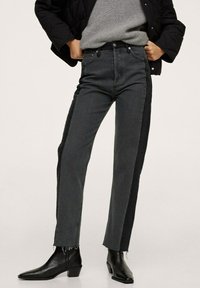 Jean denim gris foncé avec un panneau latéral noir contrastant, coupe droite, ourlet effiloché et design classique à cinq poches.