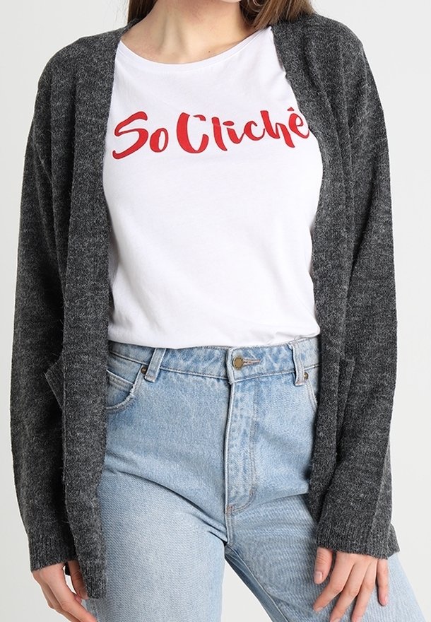 Cardigan en maille gris foncé à ouverture avant, associé à un t-shirt blanc avec un texte rouge. Un jean bleu taille haute complète la tenue.