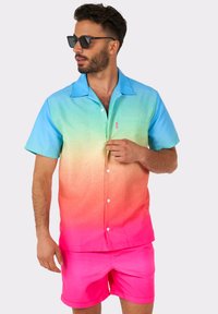 Short-sleeve button-up shirt in a gradient of blue to pink, paired with bright pink shorts. Made from smooth, lightweight fabric.