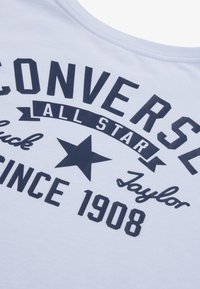 Valkoinen puuvillapaita, jossa on tummansinisellä painettuna teksti: "CONVERSE ALL STAR" tähtigrafiikan kanssa ja "SINCE 1908" erottuvilla fonteilla.