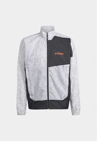 Lekka kurtka w szaro-czarnym kolorze, z zamkiem błyskawicznym, wzorem w paski oraz pomarańczowym logo na piersi. Długie rękawy i elastyczne mankiety.