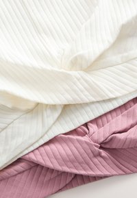 Trois morceaux de tissu : un tissu blanc texturé côtelé en haut, un tissu côtelé rose pâle en dessous, avec des plis et des torsions visibles.