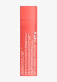Korallfärgad flytande rouge i en slät, cylindrisk pumpbehållare. Etiketten visar produktens namn, användningsanvisningar och försiktighetssymboler.