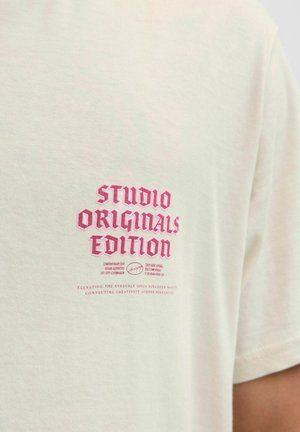 Kreemivärvi puuvillane t-särk, kus on julge roosa tikandiga tekst "STUDIO ORIGINALS EDITION" ning kõrvalla väiksem tekst. Lühikesed varrukad, tavaline lõige.