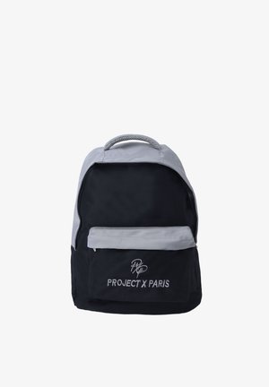 Mochila negra y gris con bolsillo frontal con cremallera y asa superior, con "PROJECT X PARIS" bordado en el bolsillo delantero.