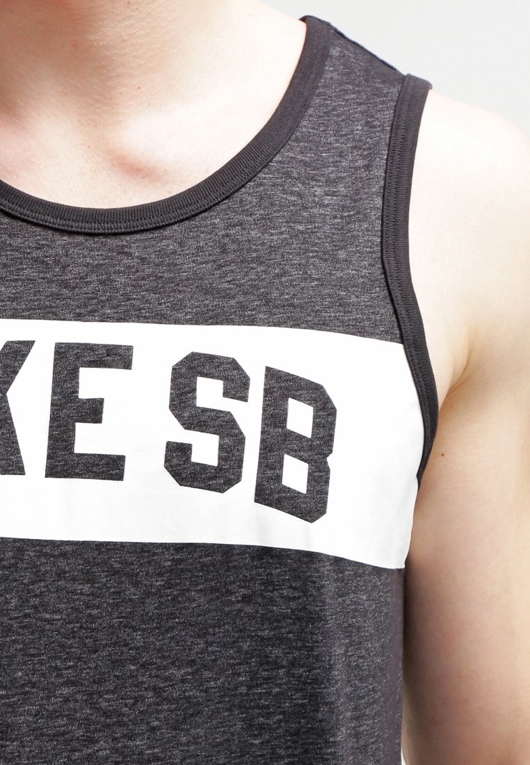 Graues Tanktop aus einem weichen Stoff, mit einem weißen horizontalen Streifen und fetten schwarzen Buchstaben "IKE SB." Klassischer Rundhalsausschnitt und ärmelloses Design.