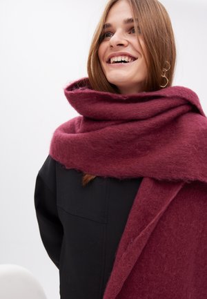 Scialle di lana bordeaux con una finitura morbida e testurizzata, avvolto intorno al collo. Presenta un design spesso e accogliente e si drappeggia elegantemente.