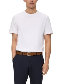 Weißes Baumwoll-T-Shirt mit kurzen Ärmeln, kombiniert mit dunkelblauen Hosen und einem braunen Wildledergürtel mit einer silbernen Schnalle.