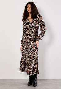 Langes, gemustertes Kleid mit V-Ausschnitt, langen Ärmeln und geraffter Taille. Es hat einen gestuften Rock in Schwarz, Beige und Rosé-Tönen.