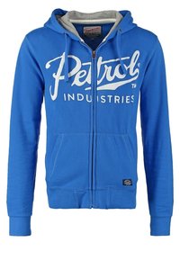 Sudadera azul con cremallera y bolsillos frontales, forro interior de la capucha en gris, cordones y logotipo blanco de "Petrol Industries" en el pecho.