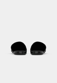 Par de slides pretos de bico aberto com palmilhas brilhantes, exibidos de frente sobre um fundo branco simples.