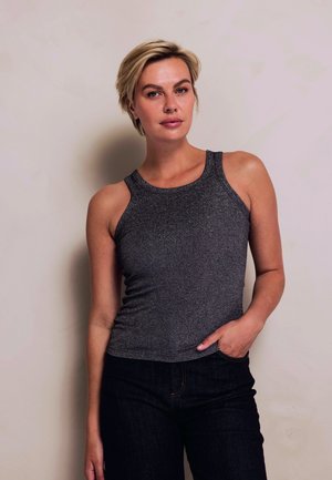 Gray ribbed tank top with a rounded neckline and sleeveless design, paired with dark denim jeans. Simple, fitted style highlighting texture.