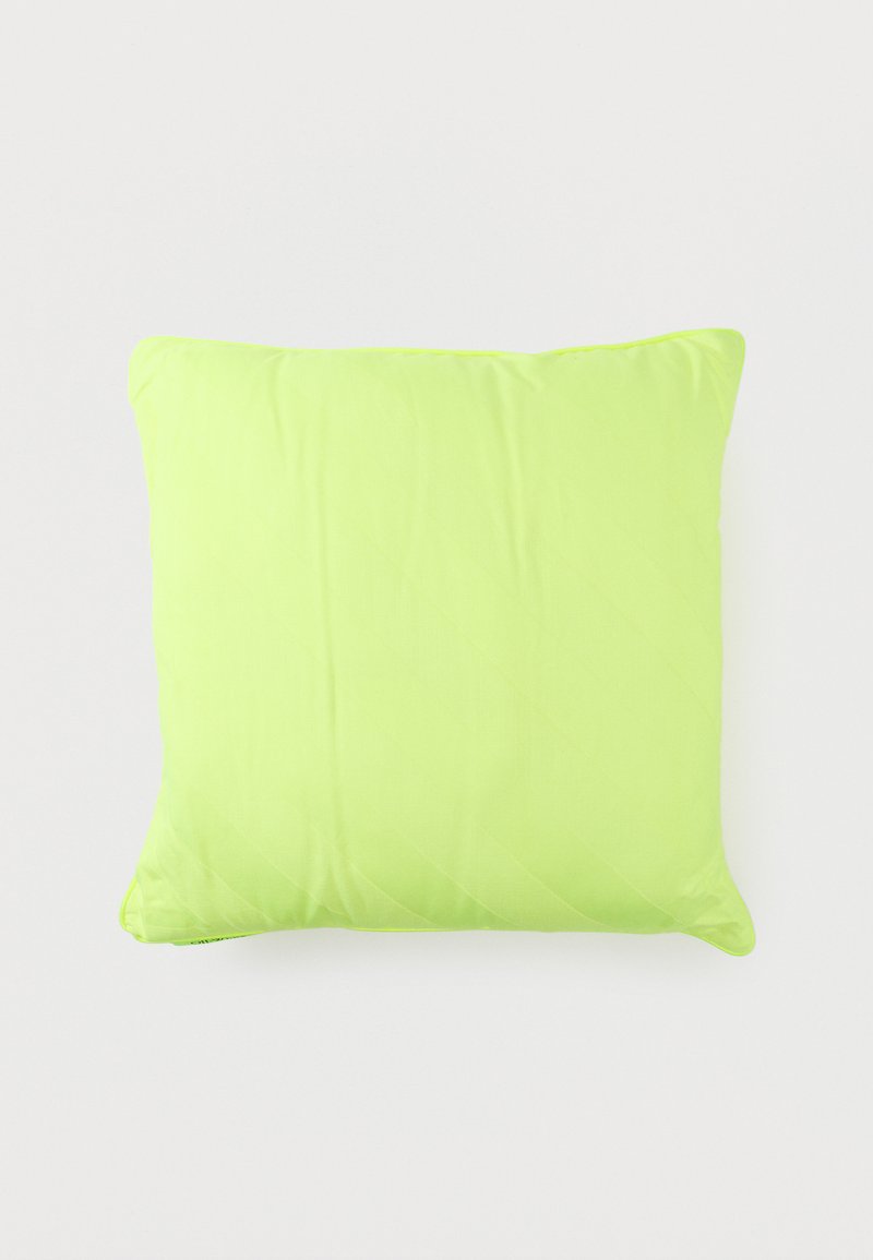 Φωτεινό πράσινο μαξιλάρι σε σχήμα τετραγώνου με λεία επιφάνεια υφάσματος, ελαφρώς τσαλακωμένο, πάνω σε απλό ανοιχτό φόντο.