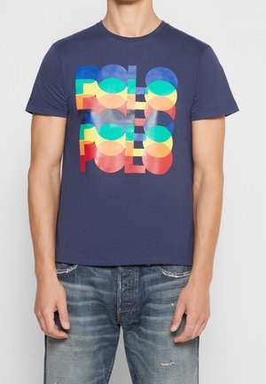Granatowa bawełniana koszulka z kolorową grafiką "POLO" w nakładających się kształtach i kolorach. Okrągły dekolt i krótkie rękawy.