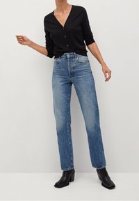 Black button-up cardigan with long sleeves, paired with light blue straight-leg jeans and black ankle boots. Simple design and tailored fit.