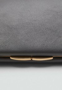 Portfolio in pelle grigia textura con un dettagliato clasp metallico dorato, caratterizzato da un design minimalista e linee pulite.
