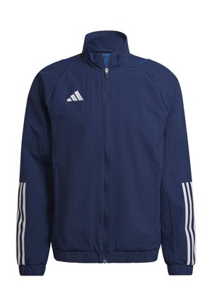 Marineblaue Sportjacke mit hohem Kragen, durchgehendem Reißverschluss, weißem Adidas-Logo und drei weißen Streifen an jedem Ärmel. Leichter Stoff, gerippte Bündchen.