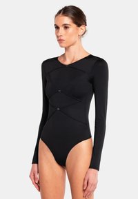 Body a maniche lunghe nera realizzata in tessuto elasticizzato, con un design a cucitura curva e bottoni decorativi lungo il torso.