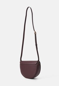 Borsa a tracolla in pelle bordeaux con forma curva a semicerchio, tracolla regolabile e chiusura a pattina rotonda. Texture liscia con hardware minimale.