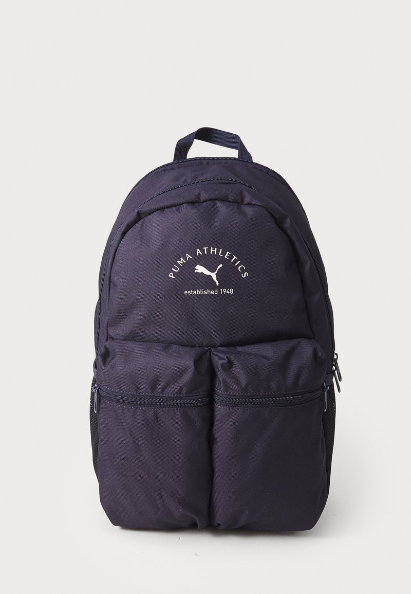 Mochila Puma de color azul marino con un logotipo prominente, dos bolsillos frontales con cremallera, correas para el hombro acolchadas y un asa de transporte en la parte superior.