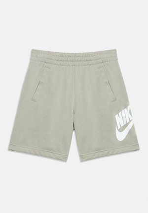 Shorts de sport gris clair avec taille élastique, poches latérales et grand logo Nike blanc sur le bas de la jambe gauche.
