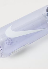 Lilla plastik vandflaske med et hvidt Nike-logo, der har en rund form, gennemsigtig krop, målemærker og et skruehætte.