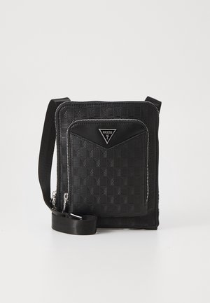 Sort Guess crossbody taske med tekstureret ternet mønster, frontlomme med lynlås, sølv lynlåse og justerbar rem på hvid baggrund.