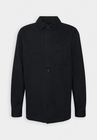 Chemise noire à manches longues avec col classique, poche avant et texture lisse. Présente une coupe droite et une fermeture à boutons.
