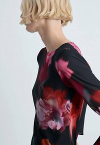 Bluză florală neagră cu modele de flori roșii și roz, cu mâneci lungi și guler rotund. Material neted cu o textură moale.