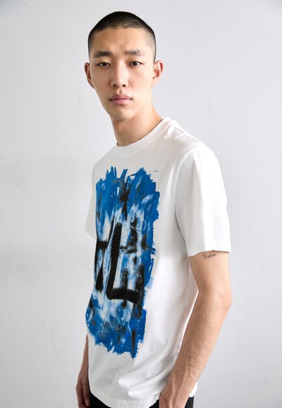 Weißes Baumwoll-T-Shirt mit blauem und schwarzem abstraktem Graphic-Design. Kurze Ärmel und Rundhalsausschnitt. Glatte Textur.