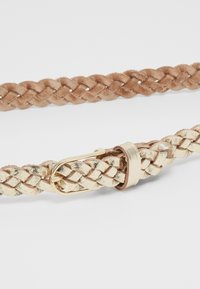 Woven pojas s bež antilopom i metalnim zlatnim detaljima, s pletenom teksturom i jednostavnom metalnom kopčom.