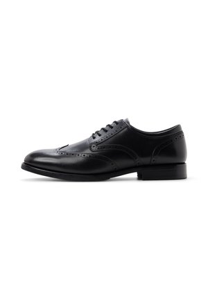 Schwarzer Herrenschuh aus Leder mit Brogue-Details, geschlossener Schnürung und niedrigem, geschichtetem Absatz auf weißem Hintergrund.