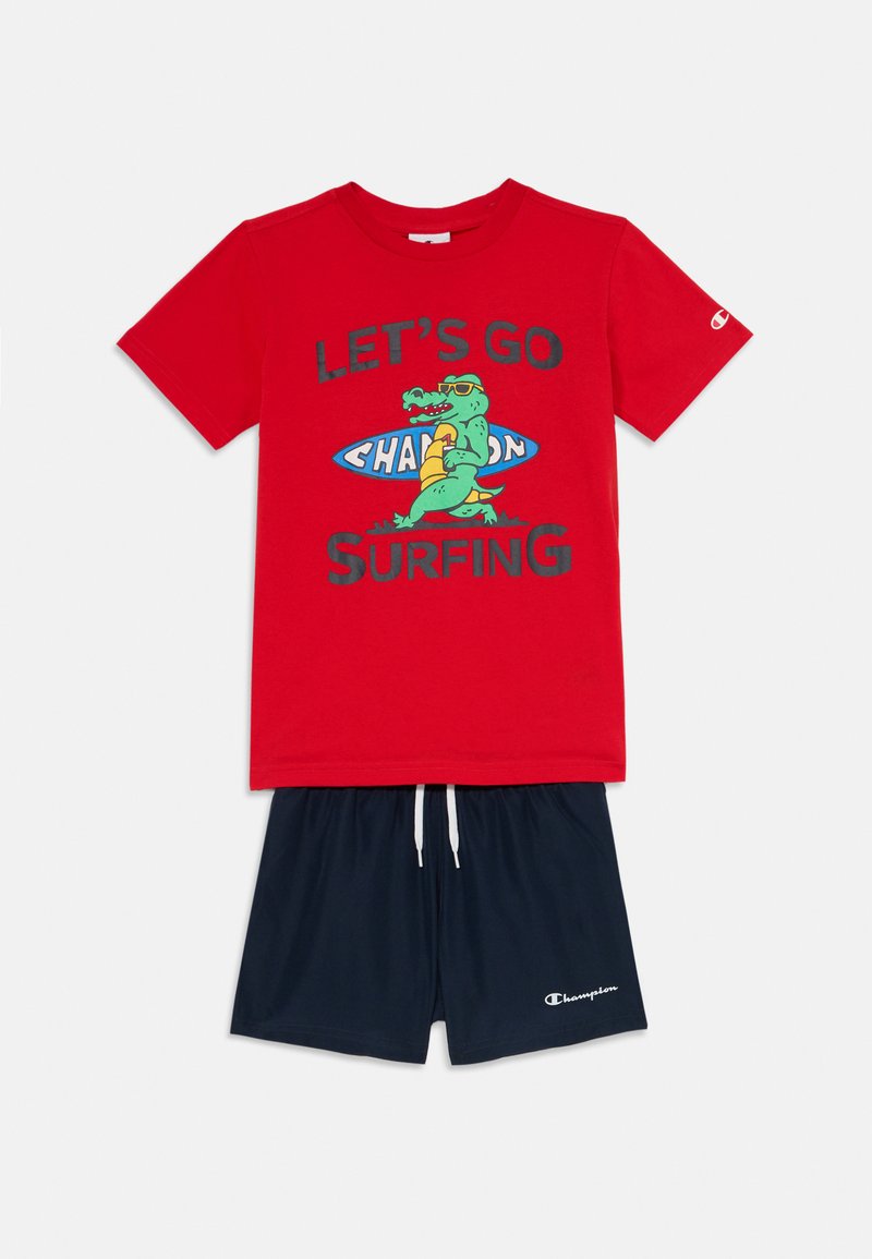 Camiseta de algodón roja con el estampado "VAMOS A SURFING" y un gráfico de dinosaurio verde. Los pantalones cortos azul marino tienen una cintura elástica y un logo.