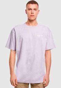 Lilla bomulds T-shirt med crew neckline, korte ærmer og trykt logo på brystet. Løs pasform med en glat overflade.
