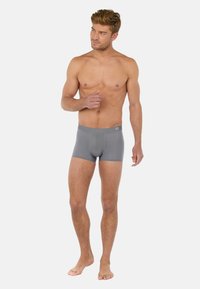 Grå boxerbriefs gjorda av ett mjukt, elastiskt material med en figurnära design och en märkesresår, som visar en lågt skuren silhuett.